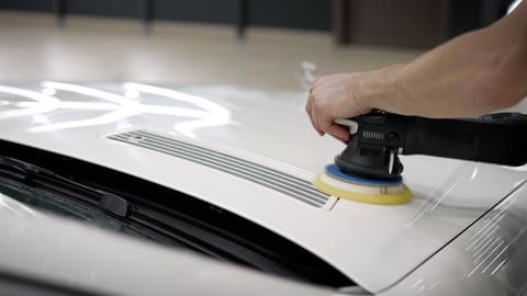 Polishing of varnish after painting the car, close-up. Grinding machine for body of auto. Grinding the car before painting. Auto mechanic grinds white car part after painting before polishing, close-up.