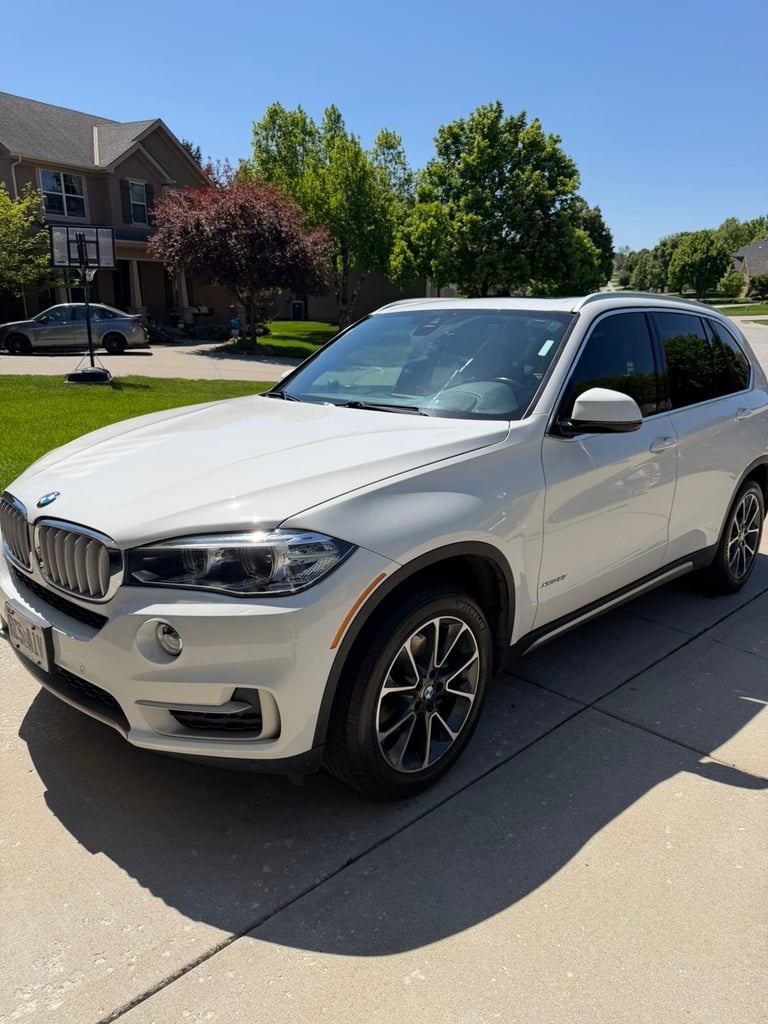 White BMW X5 luxury SUV parked in a residential driveway on a sunny day